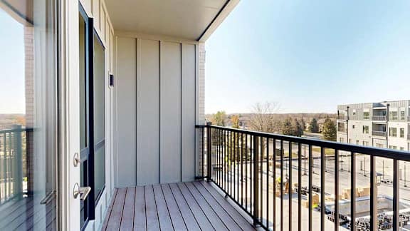 A balcony with a black metal railing, overlooking the courtyard.