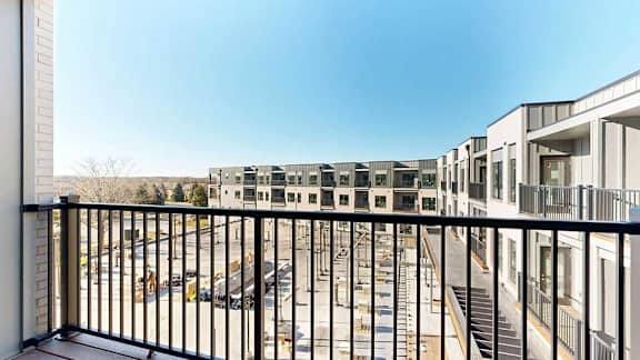 A balcony with a black metal railing, overlooking the courtyard.