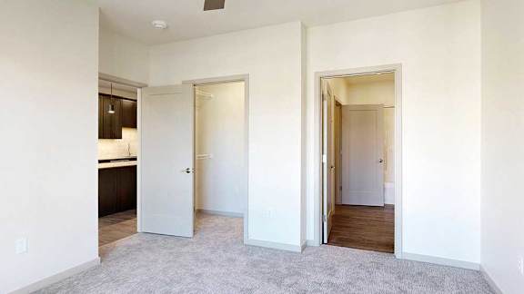 A bedroom with a ceiling fan, a large window for plenty of natural light, a walk-in closet, and an attached bathroom.