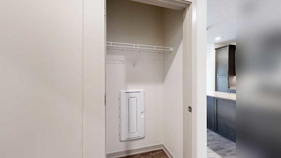 A coat closet with a built-in shelf in the front hallway.