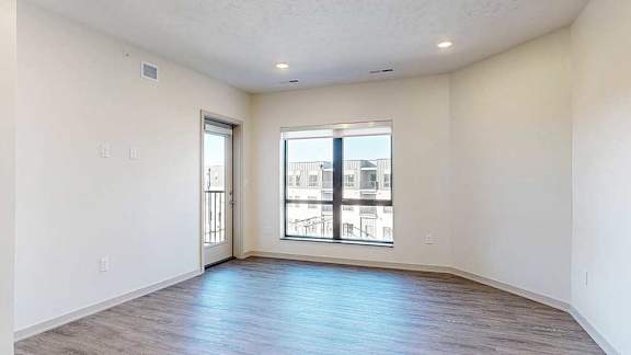 A living room with hardwood flooring, a large window, and a windowed door to a balcony.