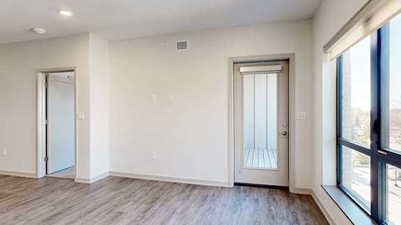 A living room with hardwood flooring, a large window, and a windowed door to a balcony.