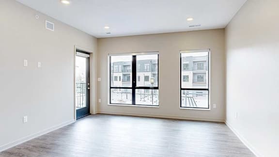 a living room with hardwood flooring, large windows, and a door to the balcony