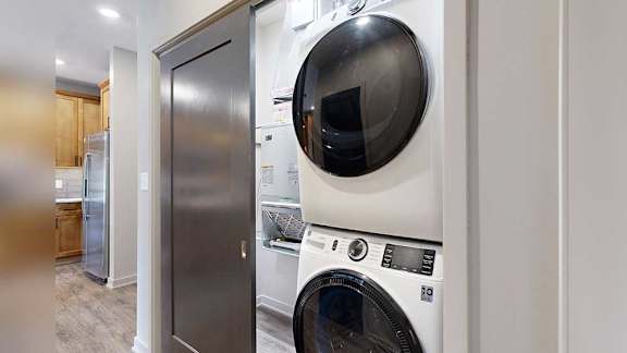 a stacked front-loading washer and dryer in a two-door closet in the front hallway