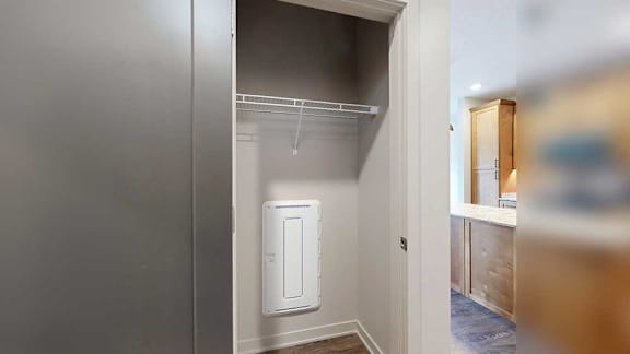 a hallway closet with built in wire shelving and a utility panel