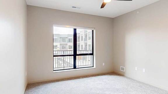 a carpeted bedroom with a ceiling fan and a large window