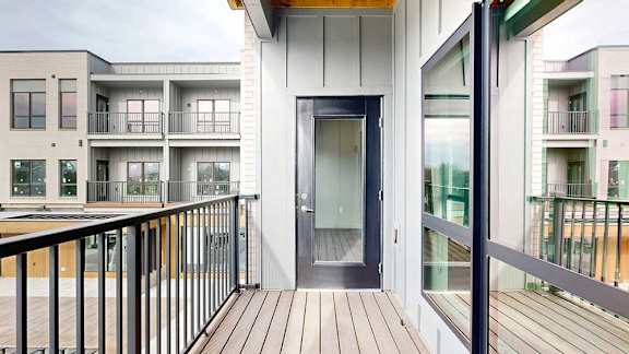 a balcony with a black metal railing, a window to a bedroom, and a glass-paneled door to the living room