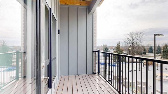 a balcony with a black metal railing, and a large window to a bedroom