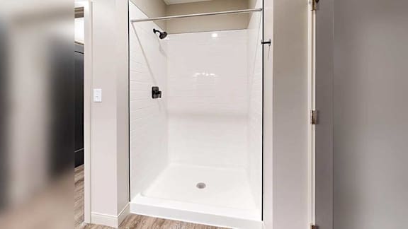 a white walk-in shower with black finished fixtures