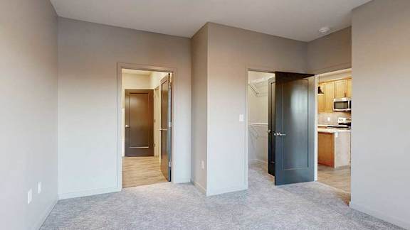 a bedroom with an attached bathroom, walk-in closet, and door to the living room