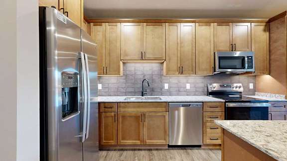 a kitchen with tan wooden cabinets and stainless steel appliances