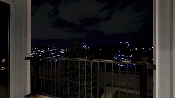 A view from a balcony at night with lights on the trees