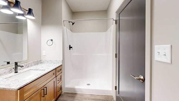 A bathroom with a white granite countertop and a walk-in shower