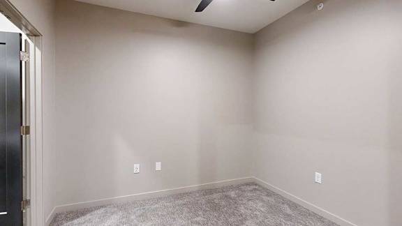 A room with a carpeted floor and a door on the left.