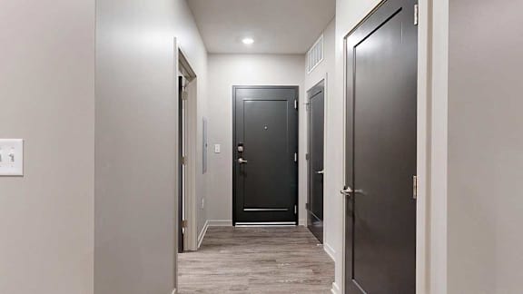 A hallway with a black door in the middle and two other doors on either side.
