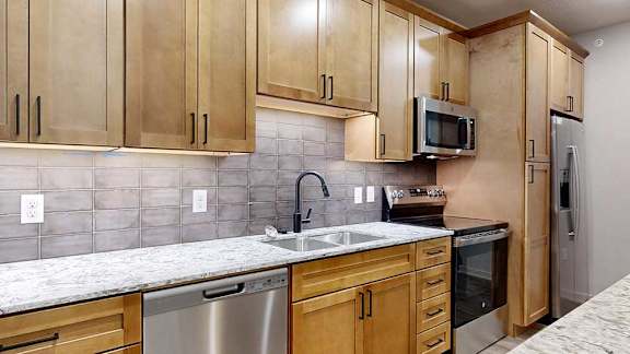 a kitchen with wooden cabinets and a light granite countertop.