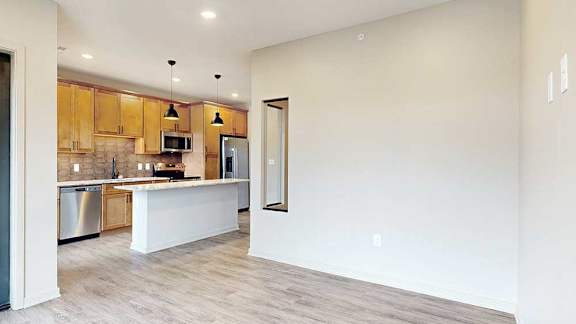 Living area with hardwood flooring, privacy wall around the sleeping area, and open view into the kitchen.