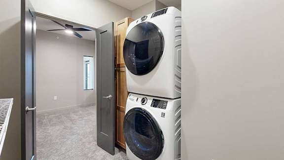 A stacked front-load washer and dryer with open double doors to the sleeping area.