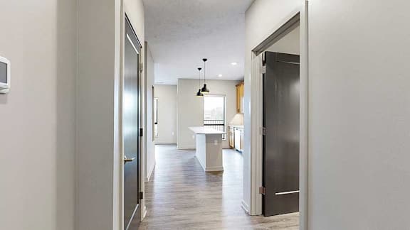 Entryway hallway leading to kitchen with pendant lighting and wood-style floors.