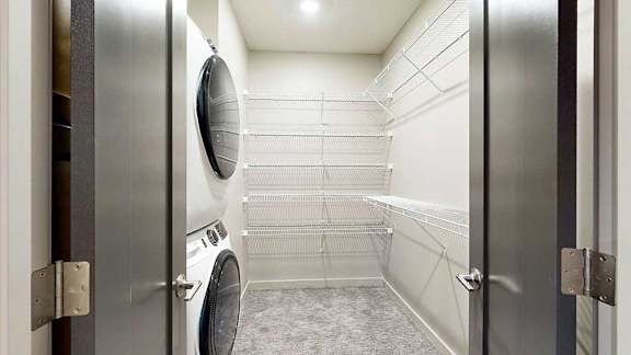 Walk-in closet with wire shelving and stacked washer and dryer on the left.