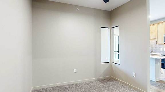 Sleeping area with carpet and two narrow windows in the privacy wall overlooking the kitchen.