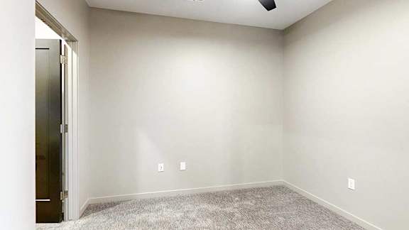 Sleeping area with carpet flooring, neutral walls, and ceiling fan above.