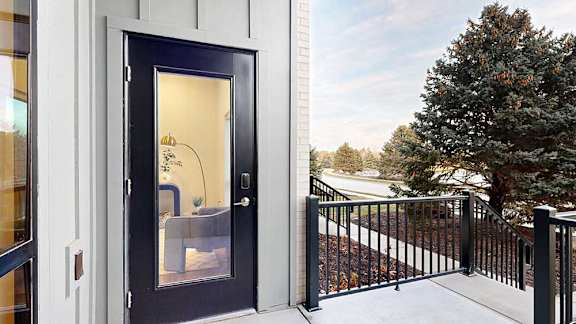 a balcony with a metal railing and a door and window leading inside the apartment
