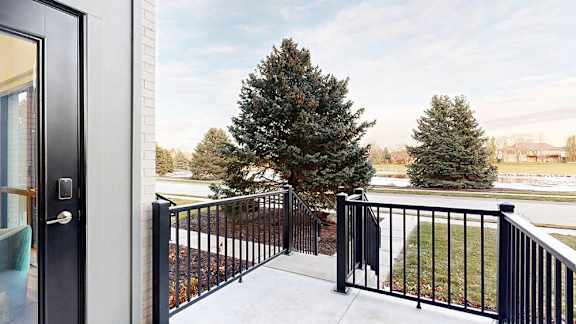 a balcony with a railing and a view of neighboring buildings and trees