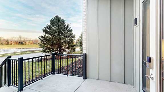 a balcony facing out toward apartment buildings and green space