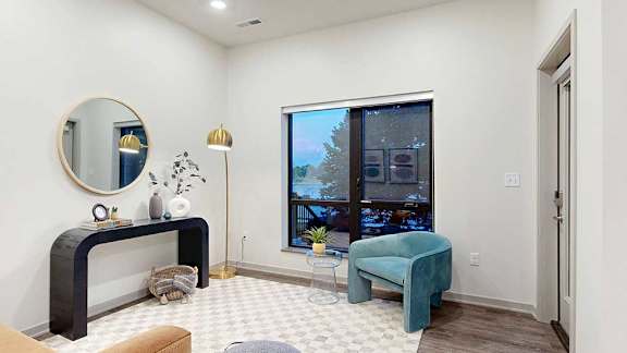 a studio apartment living area with a chair, small table, and wall-mounted artwork