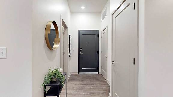 a hallway with decorative wall art and a bench, leading to other rooms