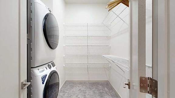 a stacked washer and dryer in a nook behind a door