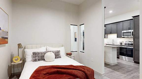 a bed with a red throw blanket and neutral-toned walls