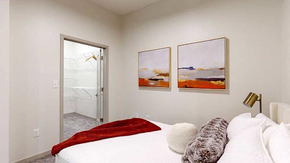 a bedroom featuring a bed with framed artwork above and modern decor accents, and a walk-in closet