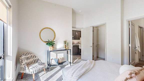 A furnished bedroom with modern furniture, a walk-in closet, and an attached bathroom.