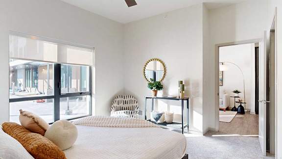 a bedroom furnished with modern furniture and a large window looking out to the courtyard