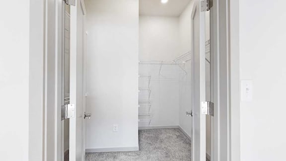 An L-shaped walk-in closet with several built-in shelves.