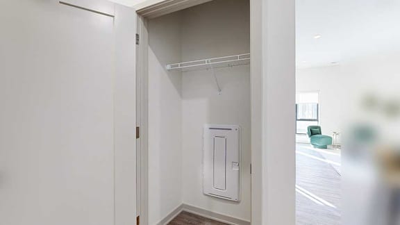 a coat closet by the front door with a built-in wire shelf and hanging space