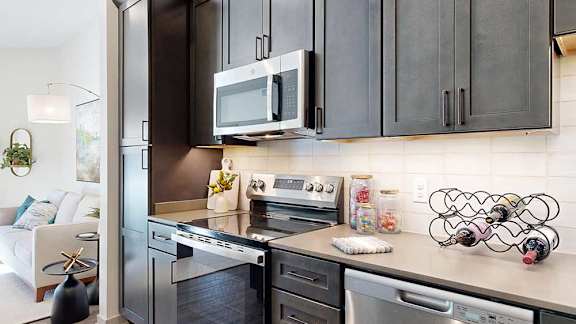 A close up of the stainless steel microwave and range in a kitchen with dark wooden cabinets.