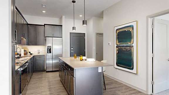 A kitchen with dark wooden cabinets, quartz countertops, an island, and stainless steel appliances.