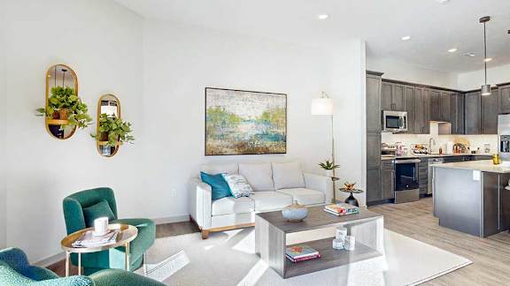A living room with a white couch, green chairs, and several modern furnishings.