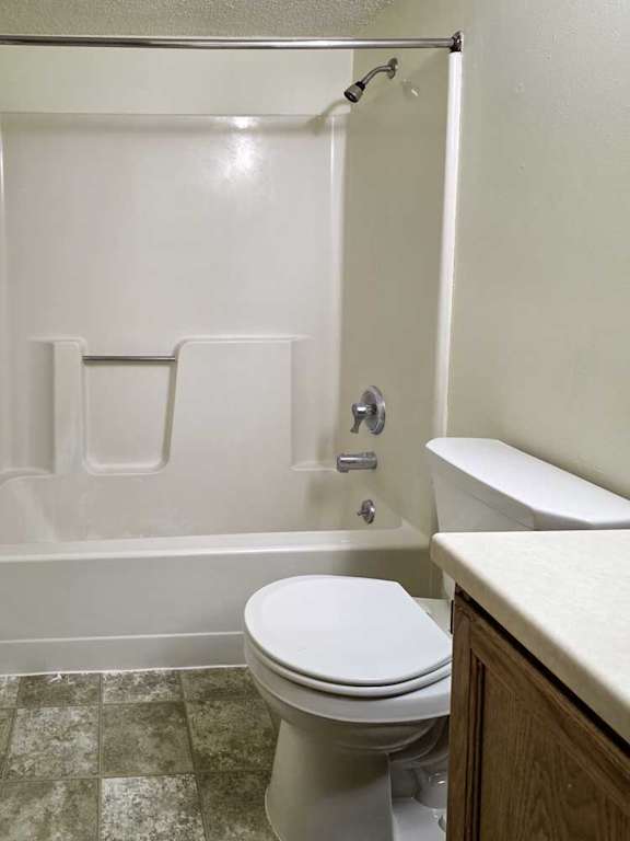 A bathroom with a sink, and a white tub shower with chrome finishes.
