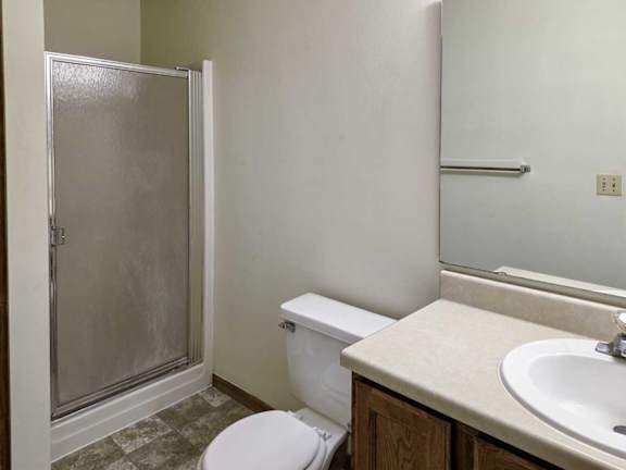 A bathroom with a sink, large mirror, and shower with a glass door.