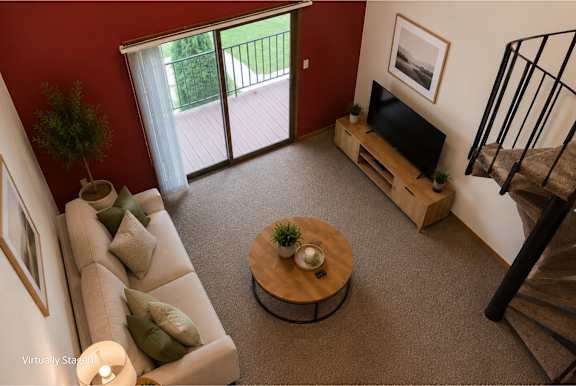 A living room with a couch, a coffee table, a television, and a staircase.