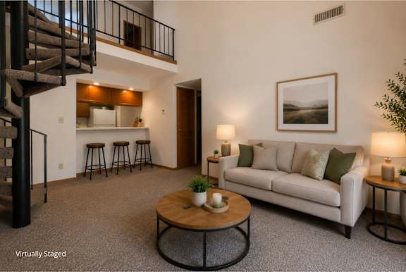 A living room with a white couch, a coffee table, and a staircase.