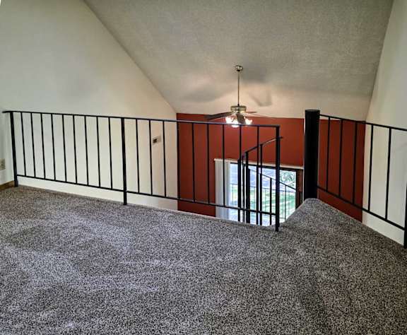 A loft area with a spiral staircase and a black metal railing.