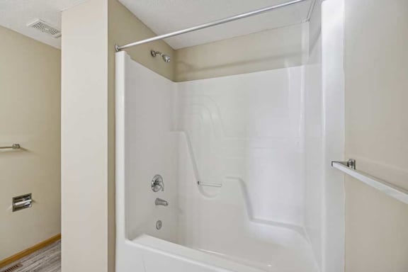 A white bathtub with a shower head and faucet.