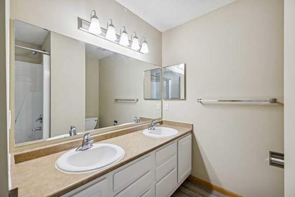 A bathroom with two sinks and a large mirror.