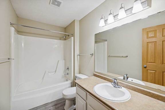 A bathroom with a toilet, sink, and mirror.