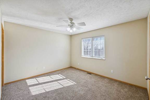 A room with a ceiling fan and a window with blinds.